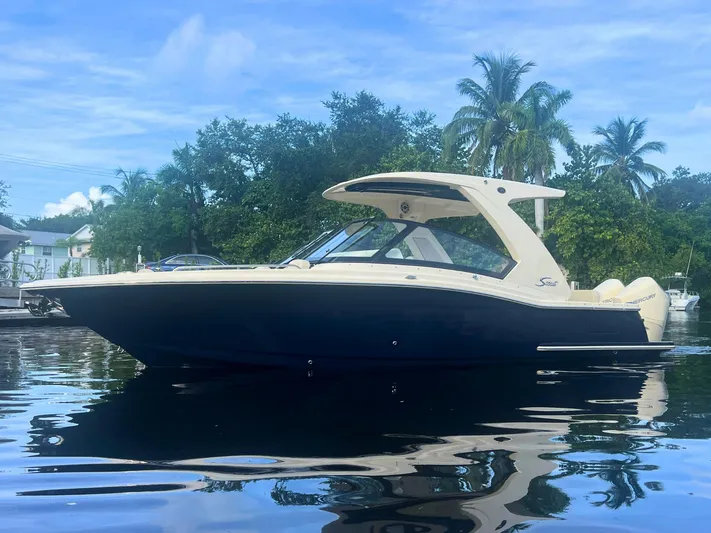  Yacht Photos Pics 2025 Scout 277 Dorado boat on calm water with lush greenery background.