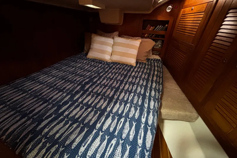Tortuga Yacht Photos Pics Cozy cabin interior of 2005 Catalina Morgan 440 with fish-patterned bedding and wooden storage.