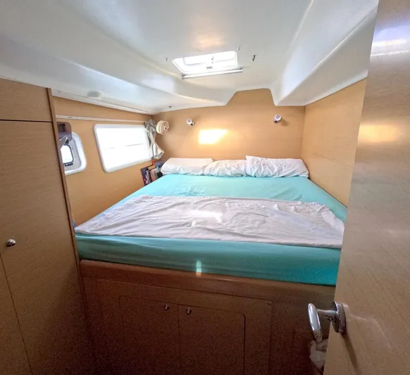 Kelapa Yacht Photos Pics Cozy cabin interior of 2016 Lagoon 380 S2 catamaran with bed and porthole windows.