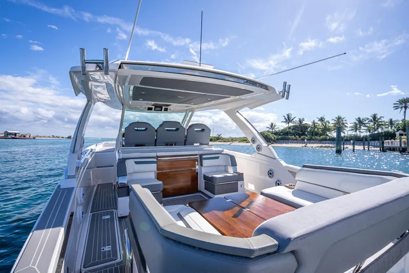  Yacht Photos Pics 2019 Tiara Sport 38 LS luxury yacht with spacious seating, docked by palm trees under a clear sky.