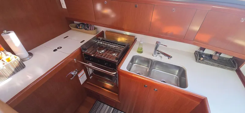 Sognare Yacht Photos Pics Galley kitchen in 2011 Beneteau Oceanis 40 yacht with stove, sink, and wooden cabinetry.