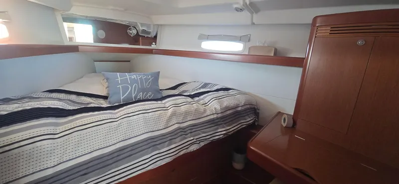 Sognare Yacht Photos Pics Cozy cabin interior of 2011 Beneteau Oceanis 40 sailboat with striped bedding and "Happy Place" pillow.
