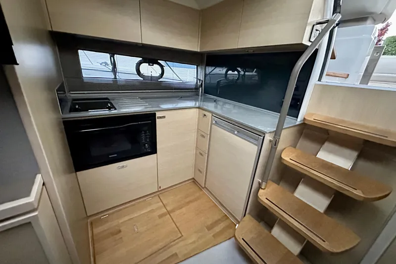 Bejul Yacht Photos Pics Modern kitchen interior of 2021 Princess V40 yacht with wooden cabinetry and stairs.
