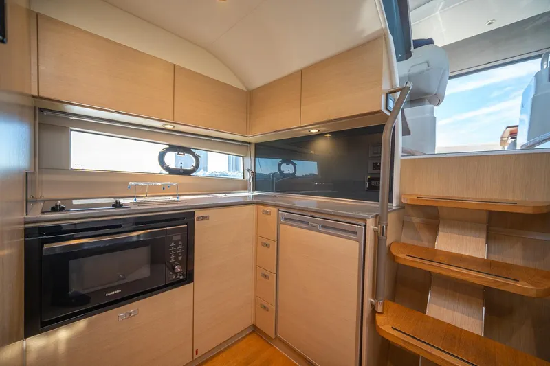 Bejul Yacht Photos Pics Modern kitchen interior of 2021 Princess V40 yacht with wooden cabinetry and appliances.