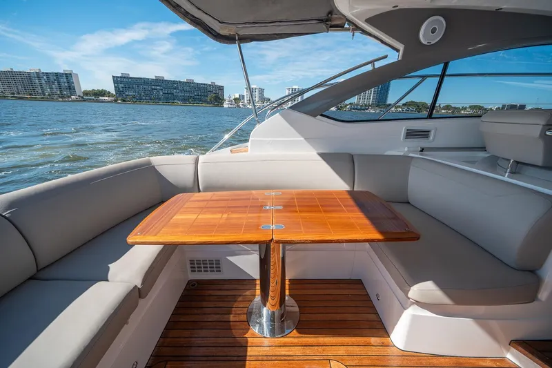Bejul Yacht Photos Pics Luxurious 2021 Princess V40 yacht interior with elegant seating and wooden table, overlooking waterfront buildings.
