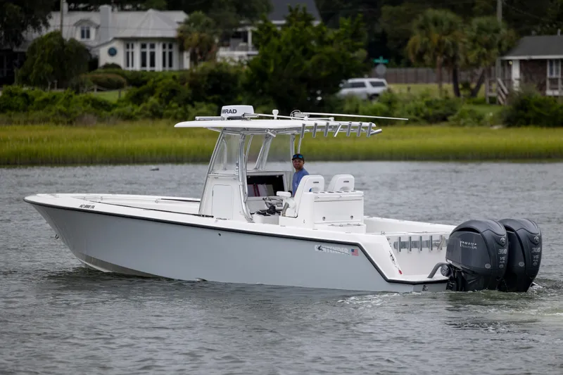  Yacht Photos Pics 2023 Contender 32 ST boat cruising on a calm waterway with lush greenery in the background.