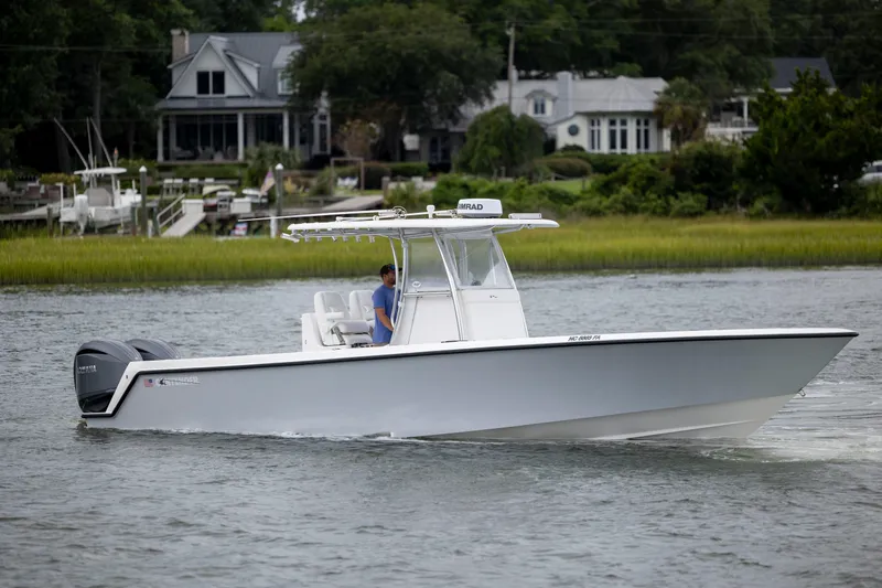  Yacht Photos Pics 2023 Contender 32 ST boat cruising on a calm river near waterfront homes.