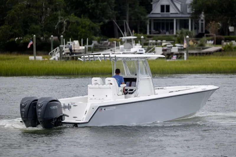  Yacht Photos Pics 2023 Contender 32 ST boat cruising on a calm waterway near a residential area.
