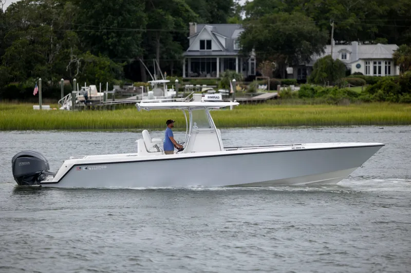  Yacht Photos Pics 2023 Contender 32 ST boat cruising on a calm river near waterfront homes.
