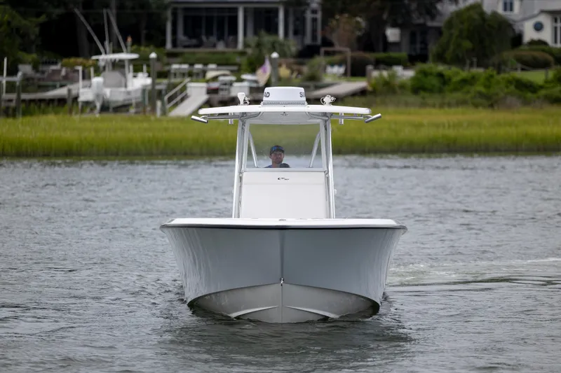  Yacht Photos Pics 2023 Contender 32 ST boat cruising on a calm river near a lush shoreline.