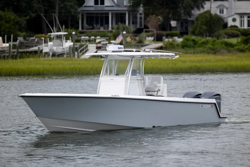  Yacht Photos Pics 2023 Contender 32 ST boat cruising on a calm river near a residential area.