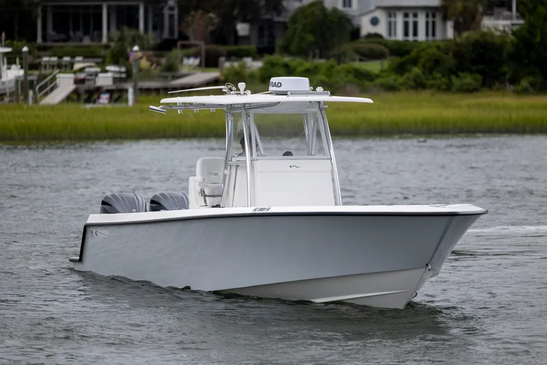  Yacht Photos Pics 2023 Contender 32 ST boat cruising on a calm river with lush greenery in the background.