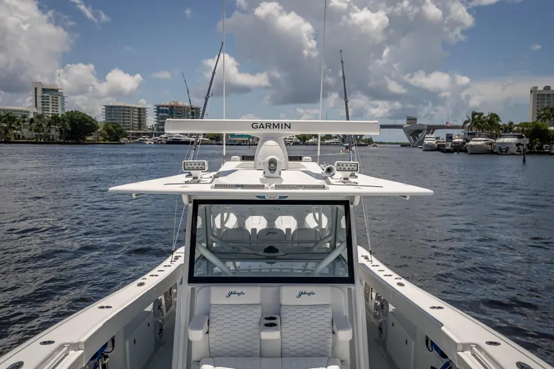  Yacht Photos Pics 2025 Yellowfin 42 Offshore boat on water, featuring Garmin equipment, cityscape background.