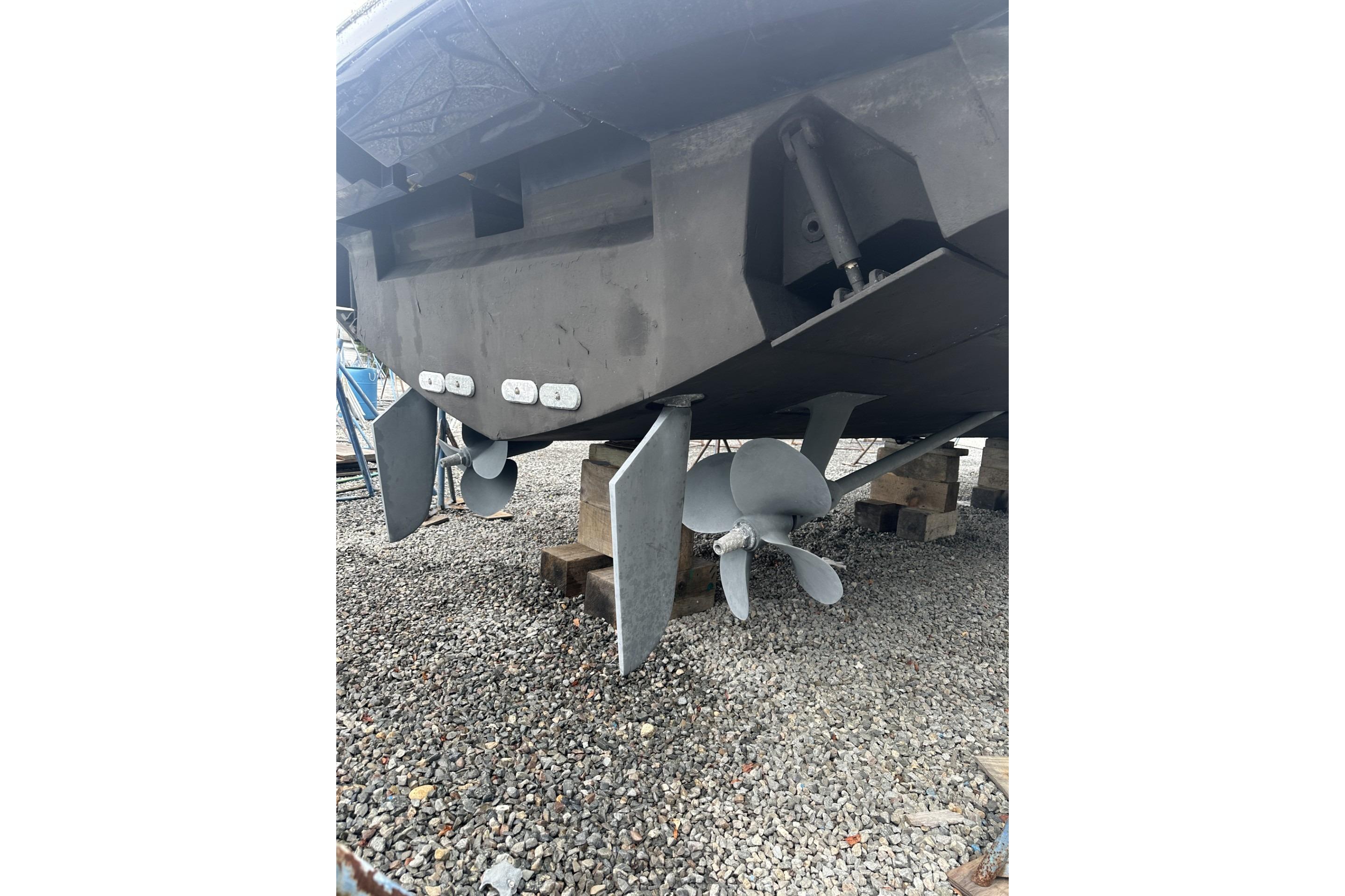 2007 Mochi Craft 44 Dolphin boat propellers and rudders on gravel.