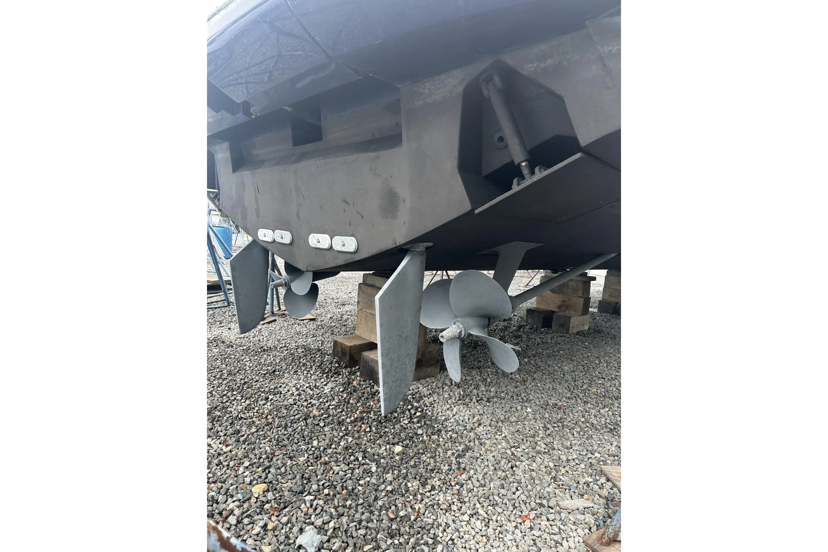 2007 Mochi Craft 44 Dolphin boat propellers and rudders on gravel.