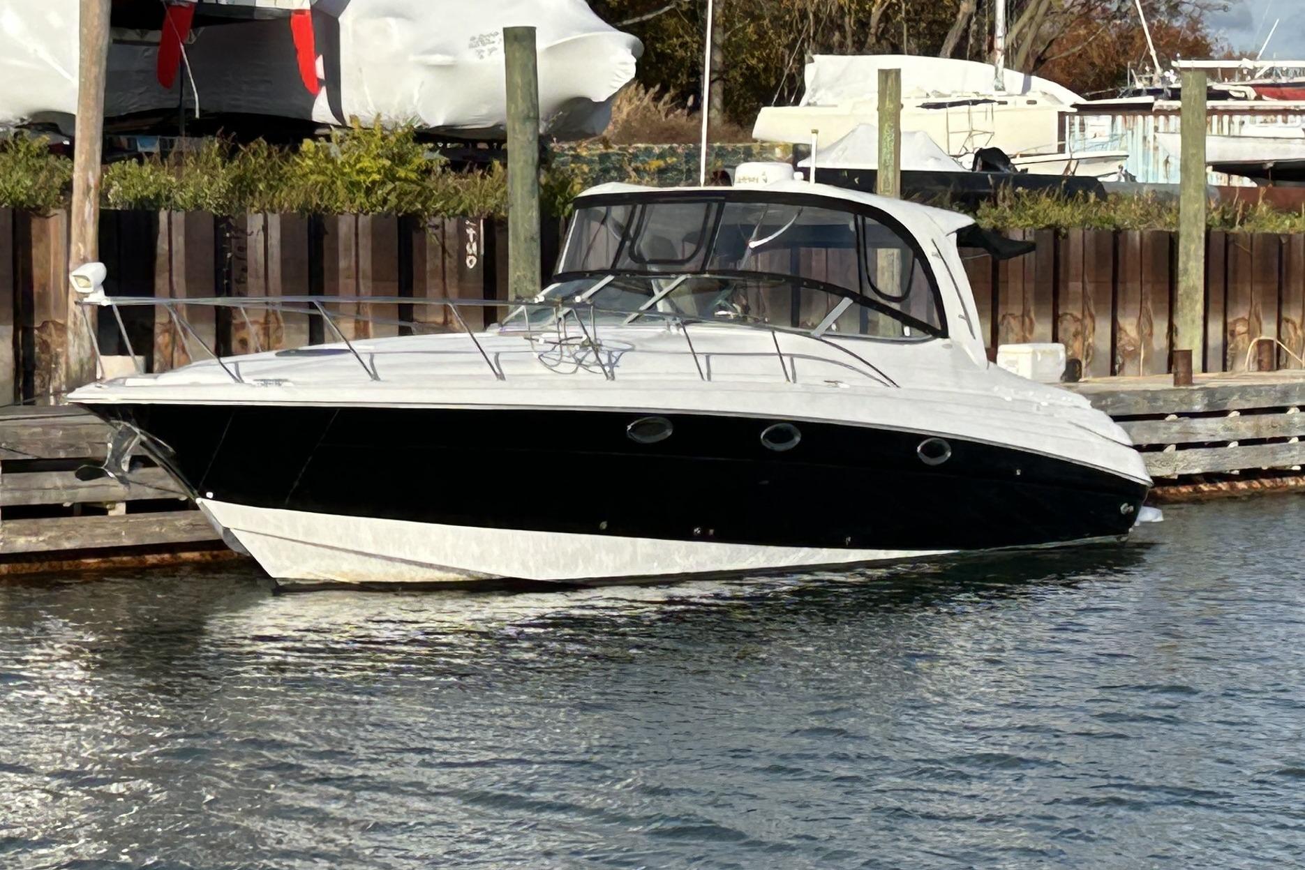 2007 Larson 370 Cabrio boat docked in a marina, featuring sleek black and white design.