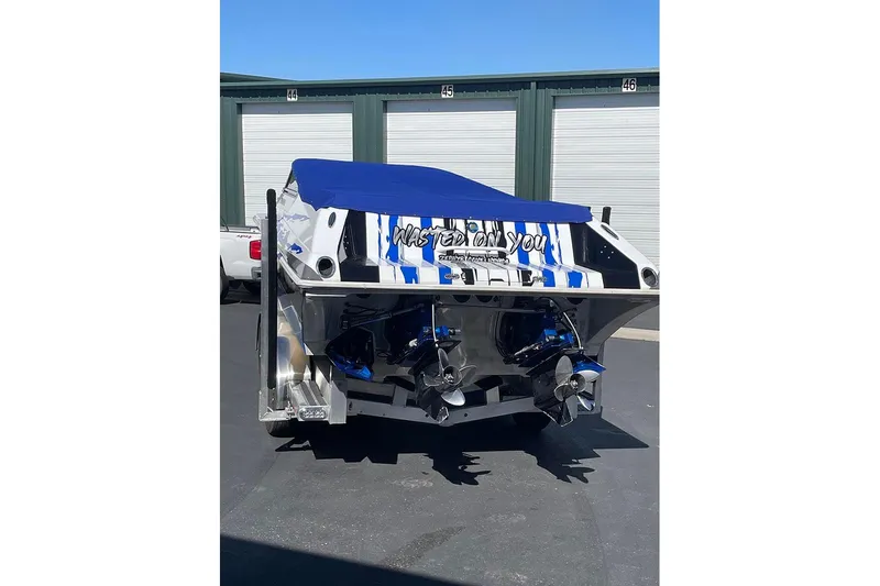  Yacht Photos Pics 2001 Fountain 35 Lightning boat with blue cover, parked near storage units.