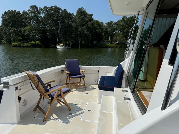 Its A Blast Yacht Photos Pics 2010 Sabre 52 Salon Express yacht deck with chairs, overlooking serene water and lush greenery.