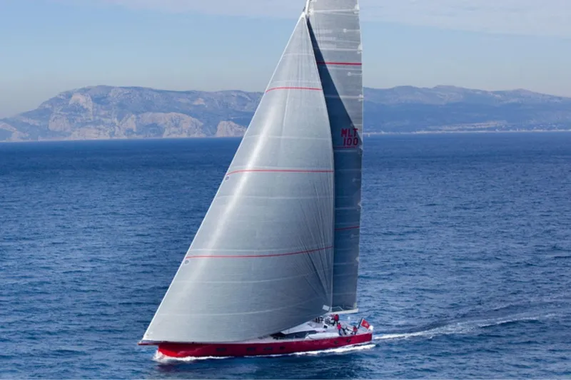 Nomad IV Yacht Photos Pics 2013 Maxi Dolphin Cruiser-Racer sailing on open sea with mountainous backdrop.