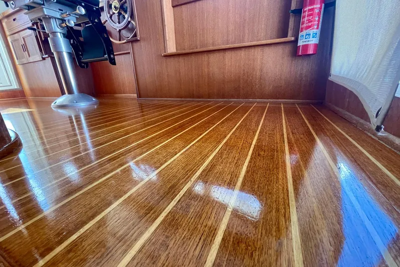 Slainte II Yacht Photos Pics Polished wooden floor inside 2008 Nordic Tug 42 boat, featuring steering wheel and fire extinguisher.