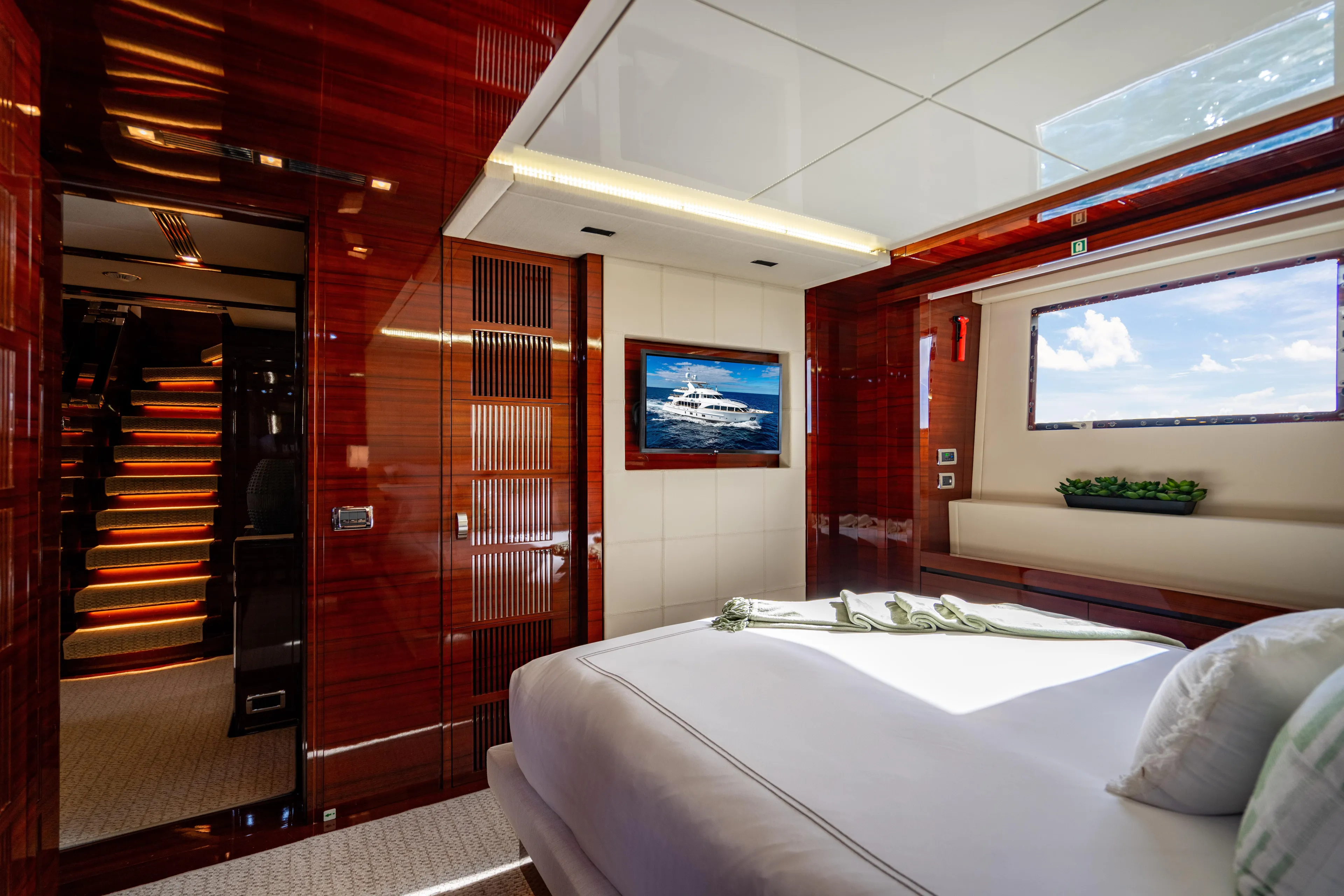 Allora Yacht Photos Pics Luxurious Benetti Classic 121 yacht bedroom interior, featuring elegant wood finishes and scenic window view.