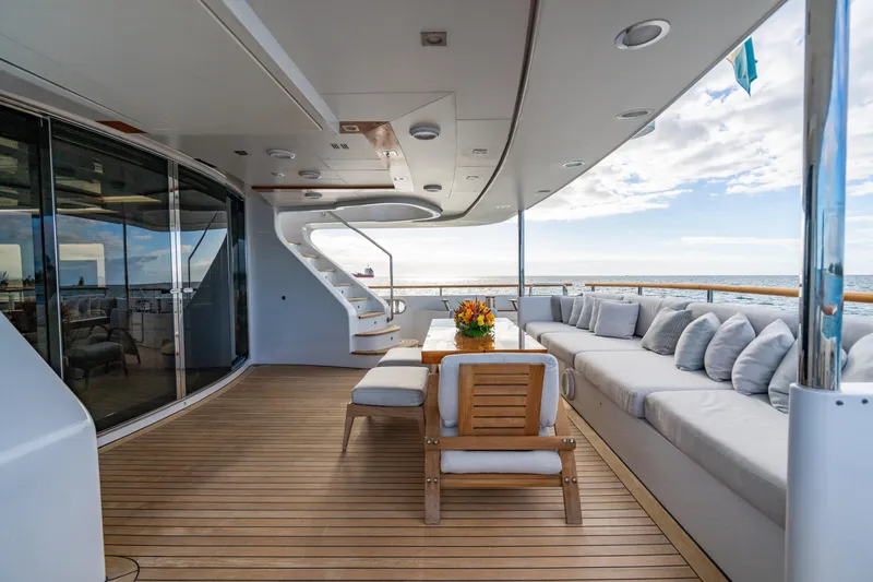 Allora Yacht Photos Pics Luxurious Benetti Classic 121 yacht deck with elegant seating, wooden flooring, and ocean view.