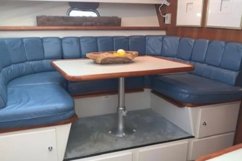 Yacht Photos Pics 1994 Carver 440 Aft Cabin Motor Yacht interior with blue cushioned seating and dining table.