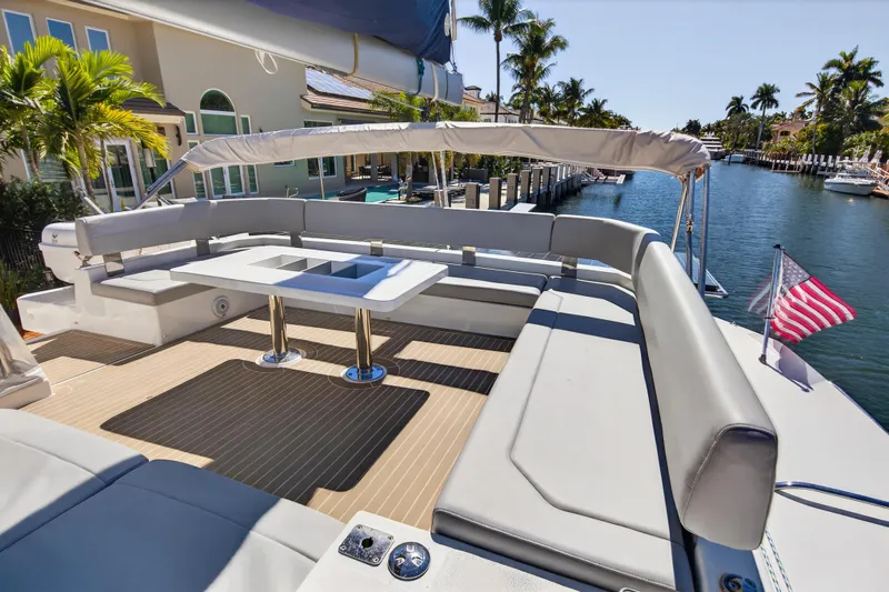  Yacht Photos Pics Luxurious 2021 Leopard 50 yacht deck with seating, table, and American flag by waterfront.