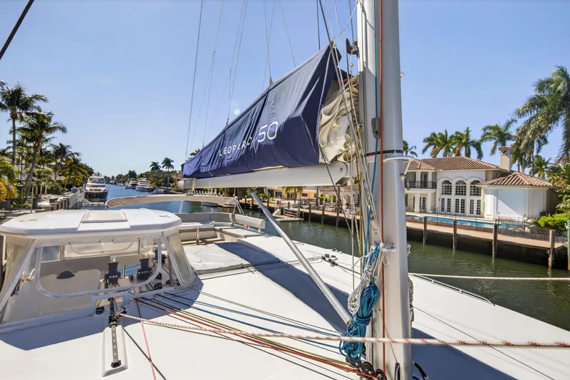  Yacht Photos Pics 2021 Leopard 50 catamaran docked in a sunny, palm-lined canal setting.