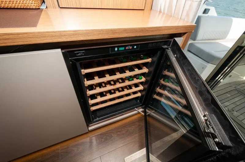 Lady Gail Yacht Photos Pics Wine cooler on 2018 Sea Ray L550 Flybridge yacht with open door and wooden shelves.