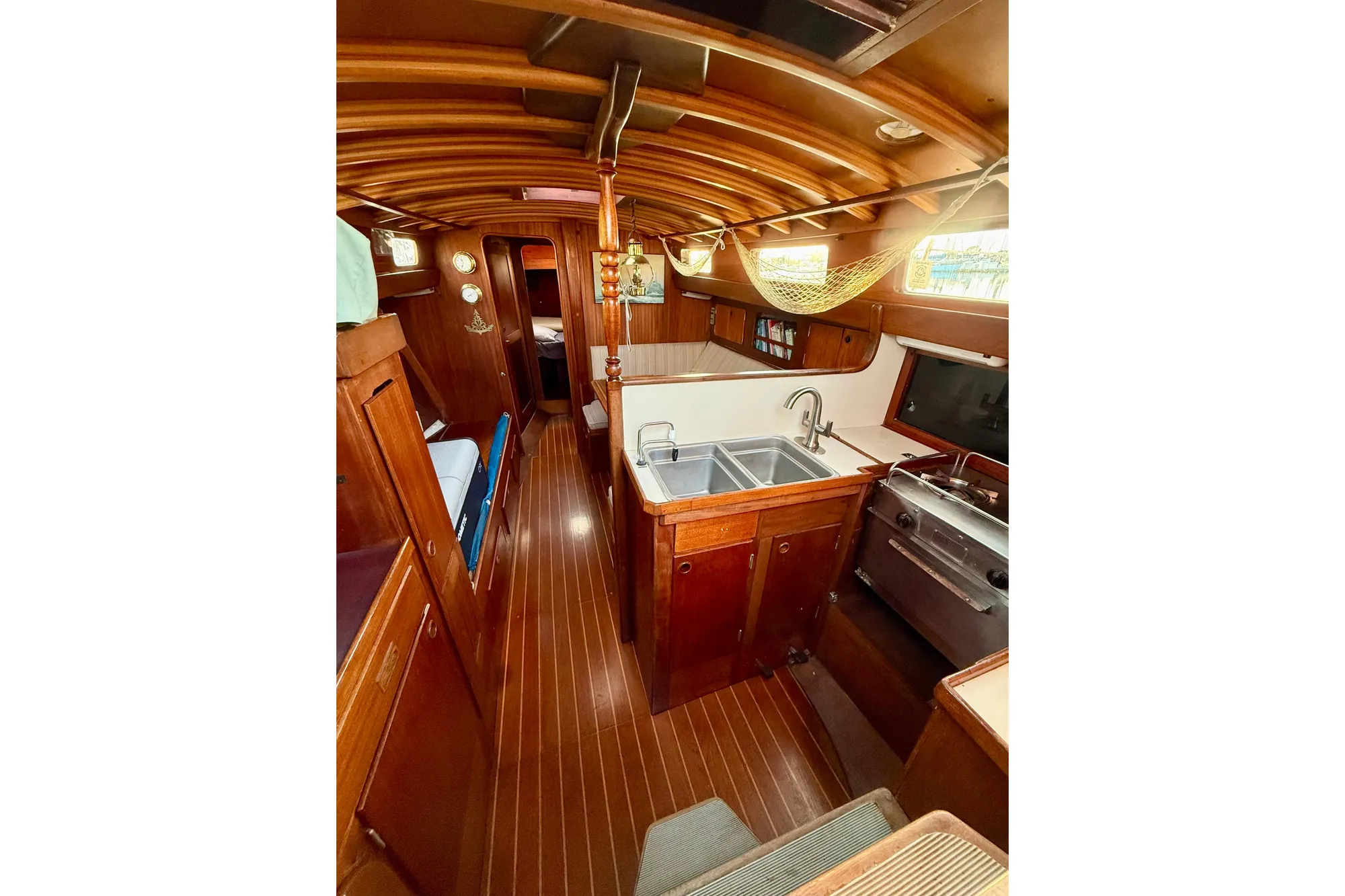 Interior of 1978 Vindo 50 sailboat with wooden finishes and compact kitchen area.