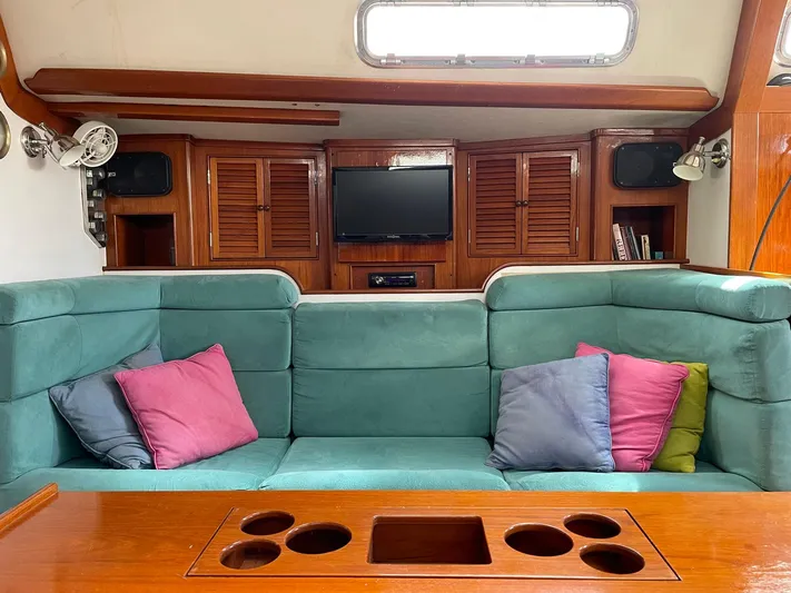 Condor Yacht Photos Pics Interior of 1996 J Boats J/160 with teal seating, colorful pillows, and wooden cabinetry.