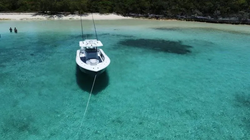  Yacht Photos Pics 2024 Yellowfin 39 boat anchored in clear turquoise water near a sandy beach.