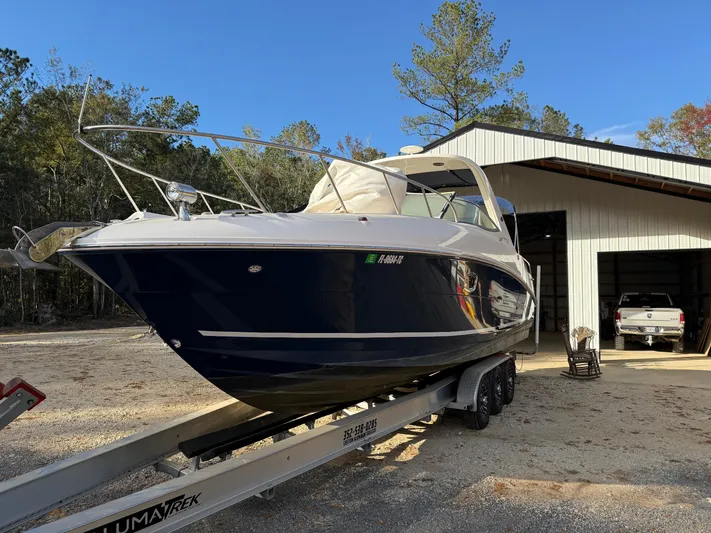 Rollin With The Flow Yacht Photos Pics 2012 Sea Ray 310 Sundancer boat on trailer near a storage building.