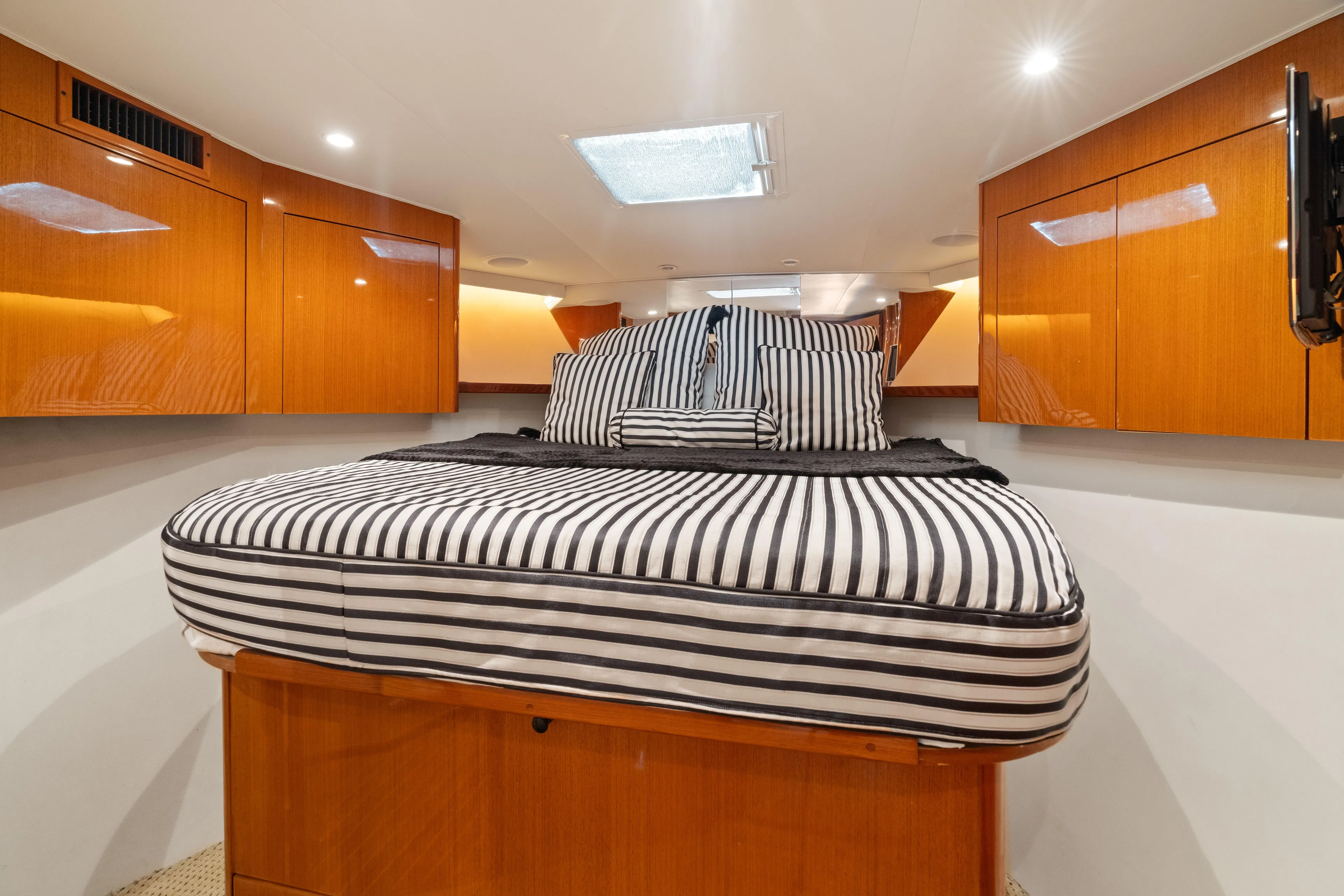 All Keyed Up Yacht Photos Pics Luxurious cabin interior of 2001 Viking 50 Express yacht with striped bedding and wooden cabinetry.
