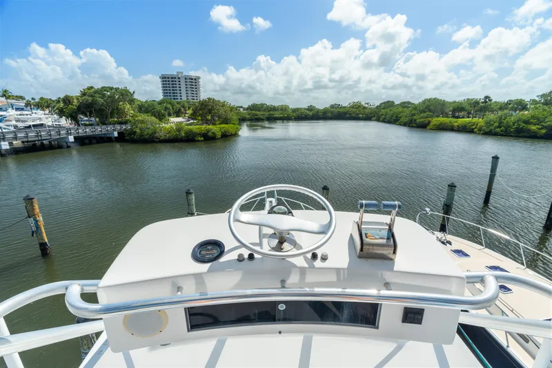 All Keyed Up Yacht Photos Pics Helm view from 2001 Viking 50 Express yacht overlooking serene waterway and lush greenery.