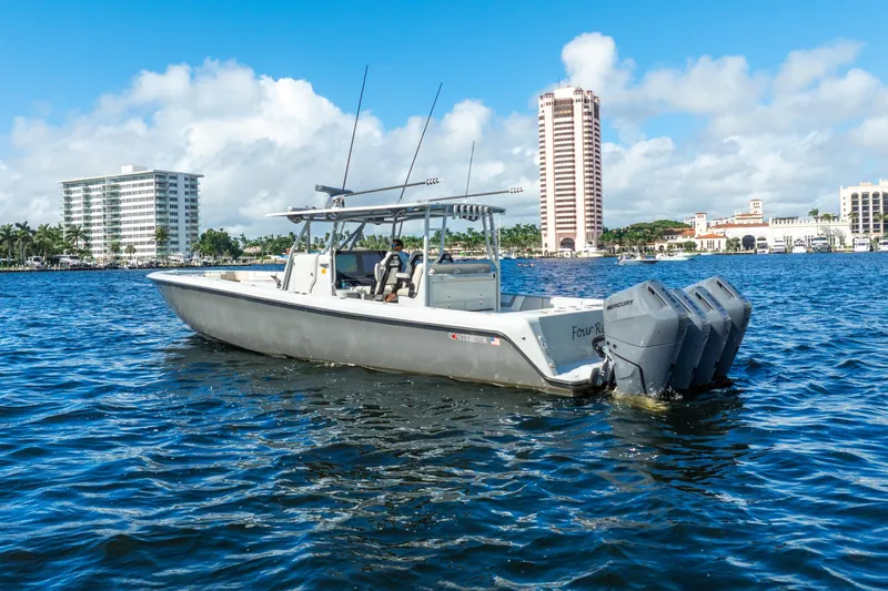 Four Reels Yacht Photos Pics 2021 Contender 44 CB boat on water with cityscape background, featuring triple Mercury engines.