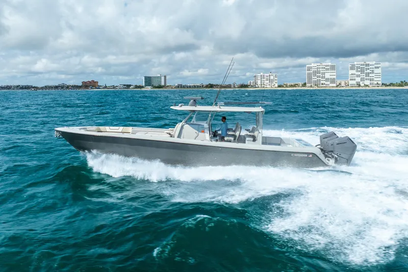 Four Reels Yacht Photos Pics 2021 Contender 44 CB boat cruising on ocean with city skyline in background.