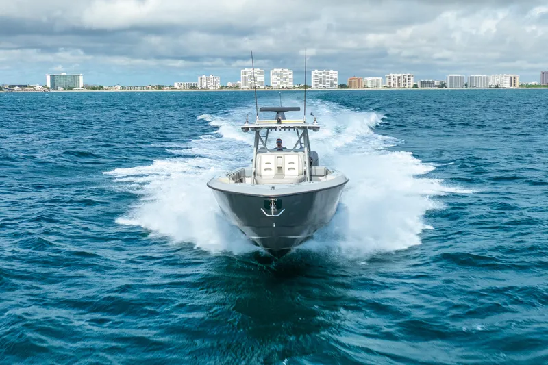 Four Reels Yacht Photos Pics 2021 Contender 44 CB boat cruising on open water near city skyline.