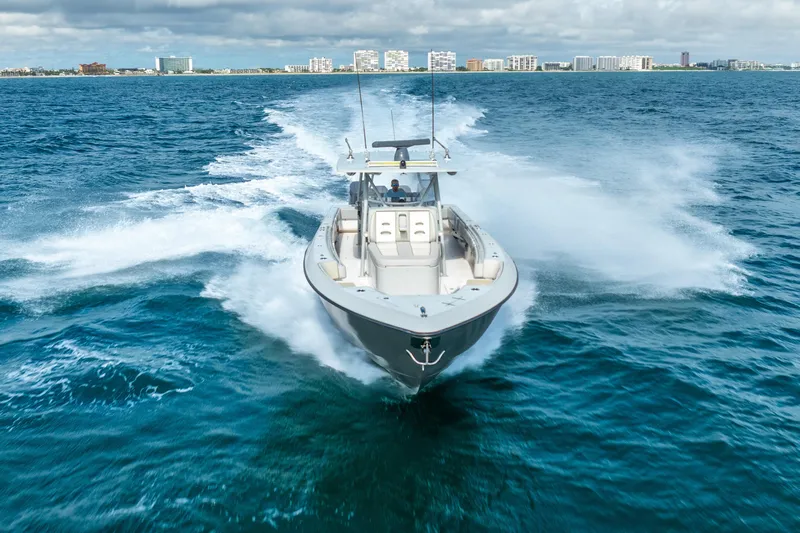 Four Reels Yacht Photos Pics 2021 Contender 44 CB boat cruising on open ocean with city skyline in background.
