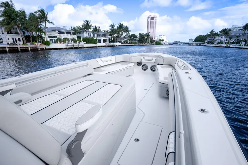 Four Reels Yacht Photos Pics 2021 Contender 44 CB boat cruising on a scenic waterway with luxury homes.