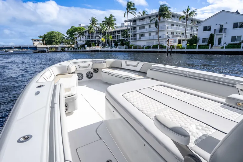 Four Reels Yacht Photos Pics 2021 Contender 44 CB boat with luxurious seating, cruising near waterfront buildings.