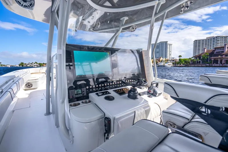 Four Reels Yacht Photos Pics 2021 Contender 44 CB boat cockpit with modern controls, steering wheel, and waterfront view.