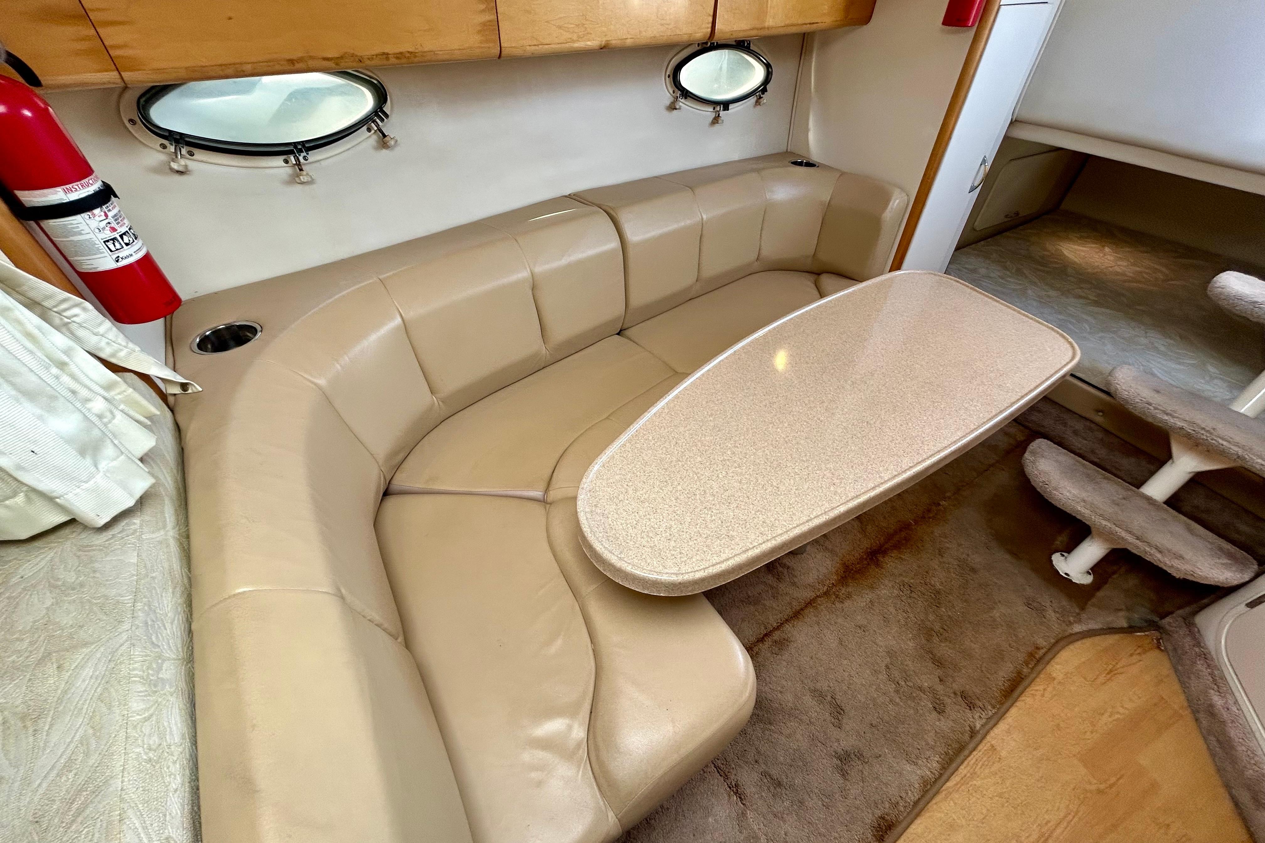 Interior of 2000 Larson 290 Cabrio boat with beige seating and table.