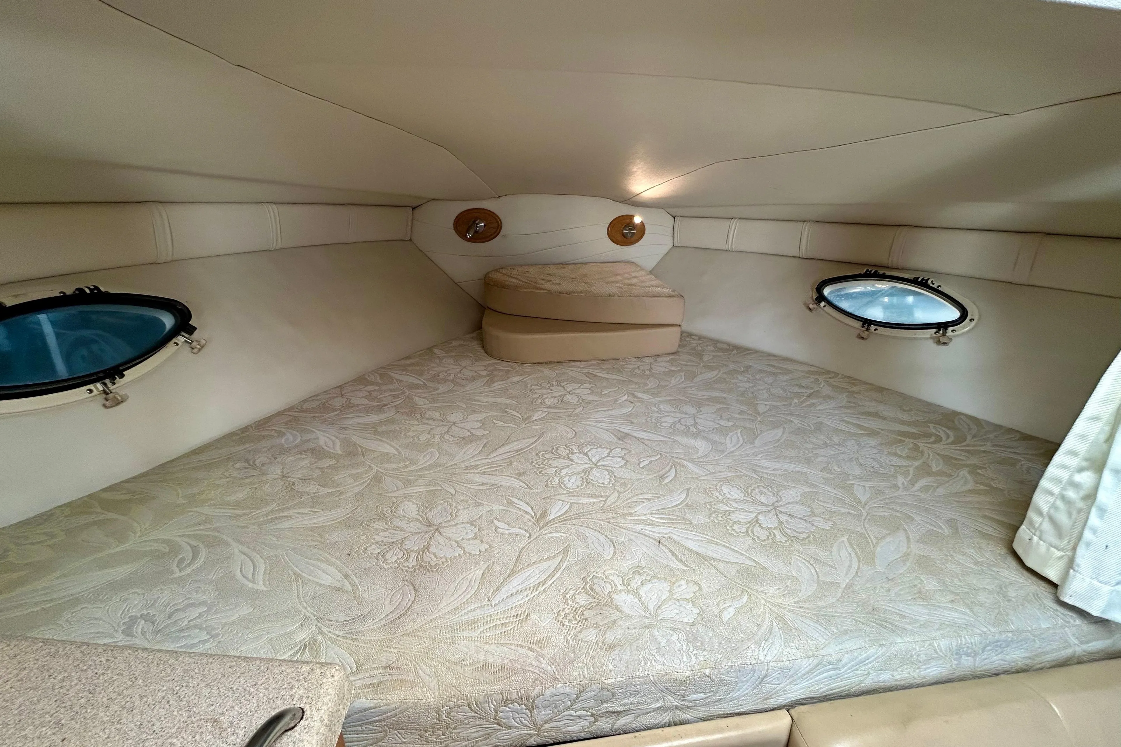 Cozy cabin interior of 2000 Larson 290 Cabrio boat with floral-patterned bedding.