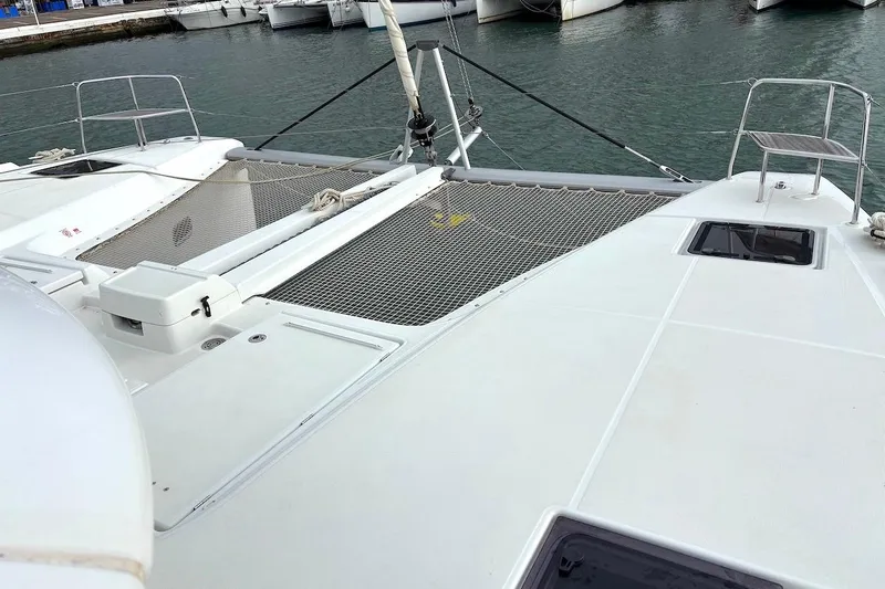  Yacht Photos Pics 2023 Lagoon 46 catamaran deck with netting, docked in marina.