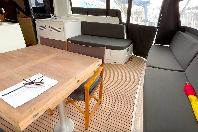  Yacht Photos Pics Interior of 2023 Lagoon 46 yacht with wooden table and cushioned seating.