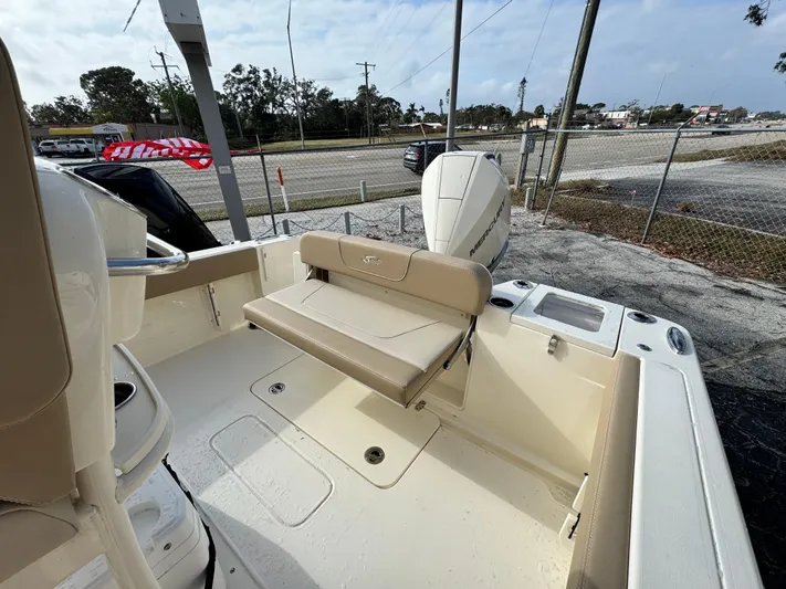  Yacht Photos Pics 2025 Scout 240 XSF boat interior with seating and motor, parked outdoors.
