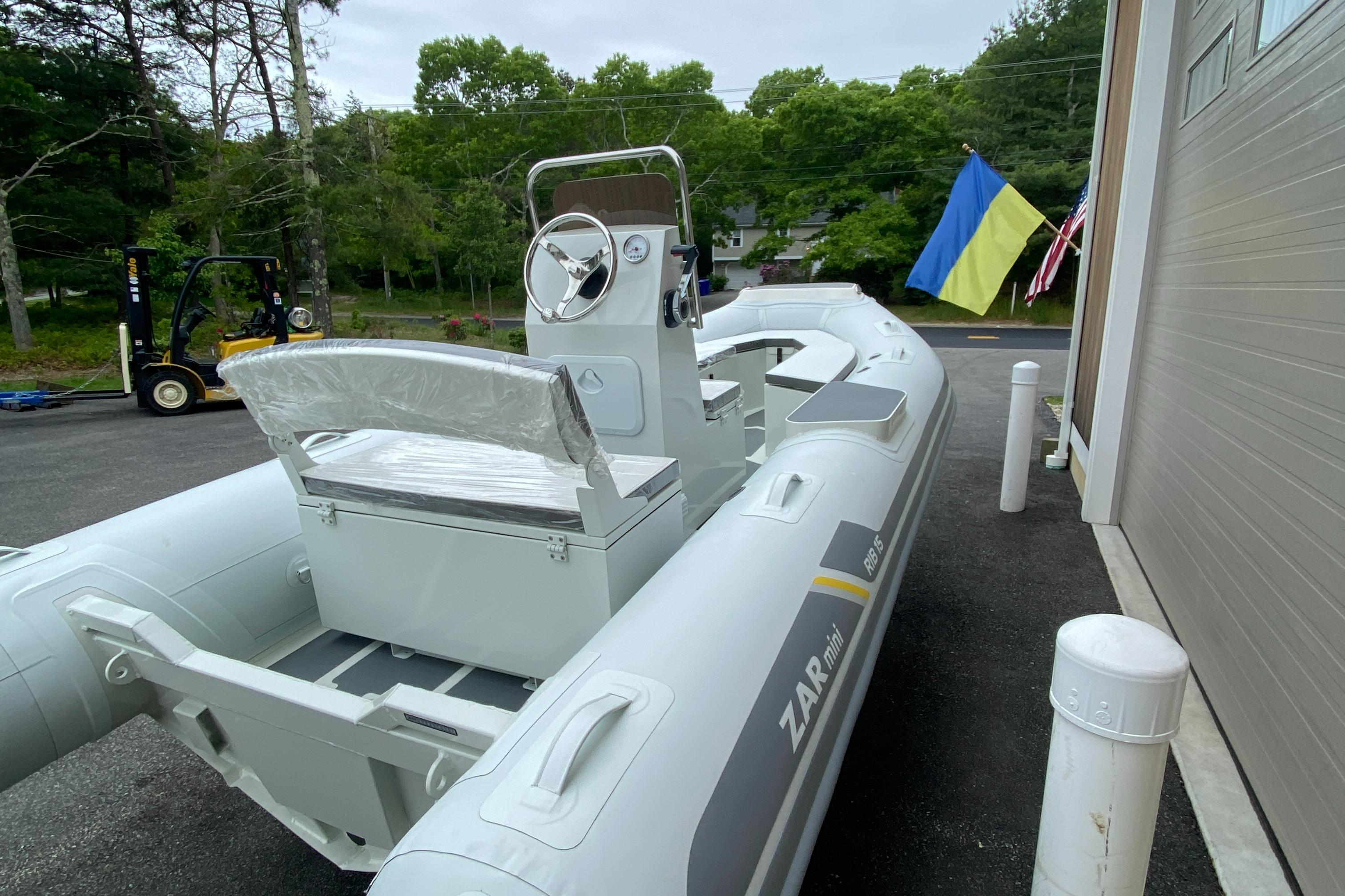 2022 ZAR Mini RIB 15 HDL Tender 60 Hp inflatable boat docked near a garage.