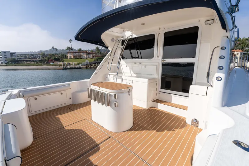 Roll The Dice Yacht Photos Pics 2005 Riviera 47 Convertible yacht deck with teak flooring, docked by waterfront homes.